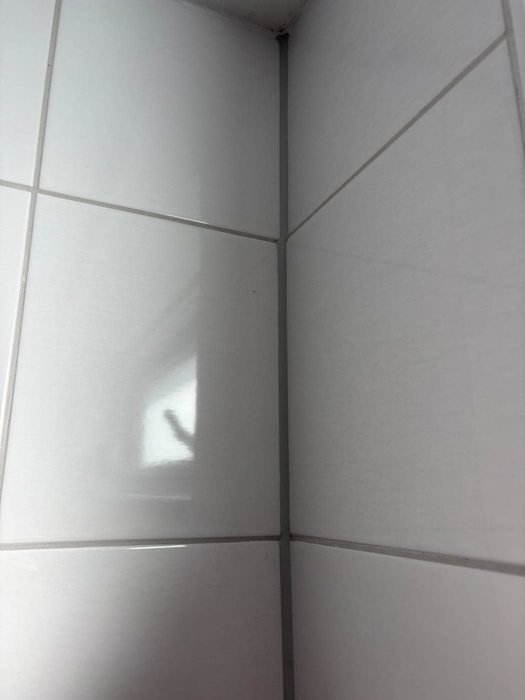 Staande hoek, witte tegels: kitwerk door Mesker Montage